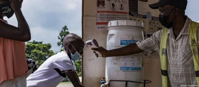 Un funcionario de salud controla la temperatura de un viajero en el cruce de Busunga entre Uganda y la República Democrática del Congo, en Bundibugyo